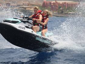 A couple enjoys an exhilarating ride on a jet ski, splashing through the waves — a perfect adventure for thrill-seekers on the water.
