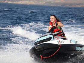 A joyful rider enjoys a thrilling jet ski adventure on the open water, showcasing the excitement of on-water activities.