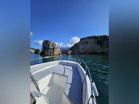 A scenic view from the bow of a boat navigating through rocky formations under a clear blue sky, showcasing the beauty of coastal exploration.