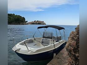 A sleek boat is docked by the shore, with a picturesque coastal view in the background, perfect for exploring the serene waters.