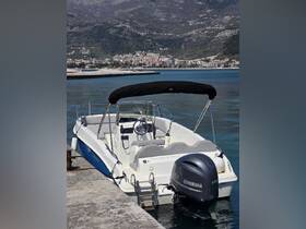 A sleek speedboat docked at the harbor, showcasing its modern design and Yamaha engine against a scenic backdrop of mountains and a coastal town.