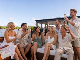 A joyful group of friends raises their glasses in a toast aboard a yacht, celebrating together in a picturesque setting — perfect for memorable gatherings and special occasions.