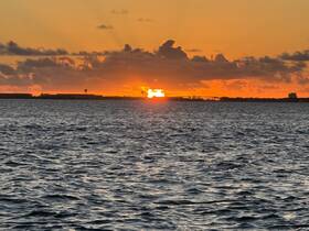 A stunning sunset over the water, casting vibrant colors across the sky and reflecting on the waves — a perfect backdrop for evening boat cruises.