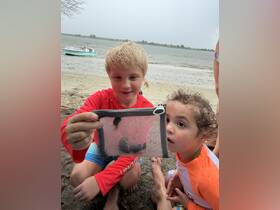 Two children excitedly observe marine life caught in a net while enjoying a day at the beach — a perfect moment of discovery and interaction with nature.