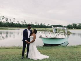 A beautiful couple shares a romantic moment by a decorated boat, perfect for wedding celebrations or engagement photos amidst serene waters.