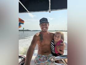 A joyful moment captured on a boat with a smiling adult and a child, showcasing family fun on the water.