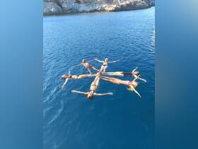 A group of friends enjoys a playful moment floating in the clear blue ocean, showcasing the joy of summer adventures on the water.