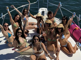 A lively group of friends celebrates on a boat, enjoying drinks and sunshine — perfect for a fun day out on the water.