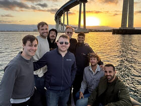 A group of friends enjoys a sunset cruise, capturing a memorable moment on the water with a stunning backdrop of the setting sun.