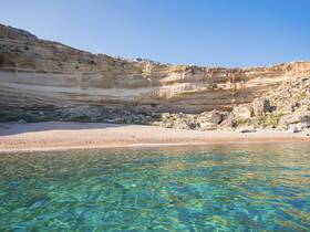 A stunning view of a secluded beach with crystal-clear waters and dramatic cliffs, perfect for a relaxing day on the coast.