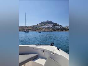 A scenic view of a boat anchored in calm waters, with a picturesque hillside village and castle in the background, perfect for exploring coastal destinations.