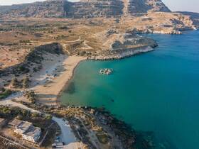A stunning aerial view of a serene beach with turquoise waters and rocky coastline, perfect for exploring the natural beauty of the area.