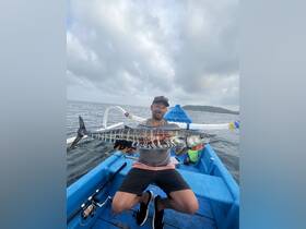 A proud angler displays his impressive catch aboard a fishing boat, showcasing the thrill of deep-sea fishing adventures.