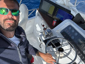 A man poses at the helm of a boat, showcasing the control console and navigation screens — perfect for those who love the thrill of steering on the open water.