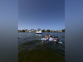 A lively group enjoys a fun day in the water, swimming and playing near their boat, creating memorable moments under the sun.