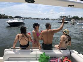 A lively group enjoys a sunny day on the water, relaxing on a boat with drinks in hand — perfect for summer parties and fun on the water.