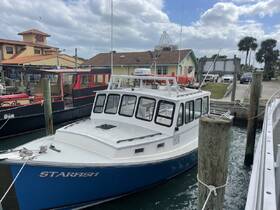 A vibrant blue boat named 'Starfish' docked at the marina, showcasing its sleek design against a backdrop of nearby buildings.