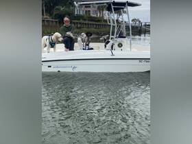 A woman proudly holds a fish while enjoying a day on the water with her two dogs aboard a boat — a perfect blend of fishing and companionship.