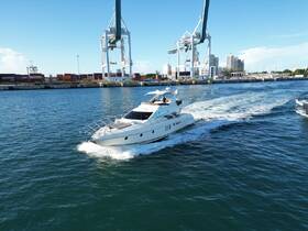 A sleek yacht cruises through the water, showcasing its elegant design against a backdrop of a bustling port and clear blue skies.