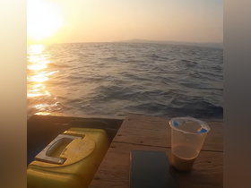 A serene view of the sunset over the water, with a glimpse of items on a surface, creating a tranquil atmosphere.