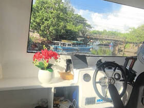 A cozy view of the helm area inside a boat, featuring a decorative plant and a glimpse of the waterway outside, perfect for showcasing the comfort of boat interiors.