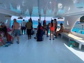 Inside view of a boat's cabin where guests are preparing for snorkeling, showcasing the vibrant atmosphere and seating arrangements.