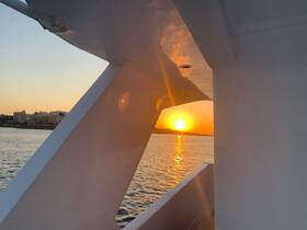 A stunning sunset view framed by the structure of a boat, showcasing the serene waters and city skyline — perfect for capturing the beauty of evening cruises.