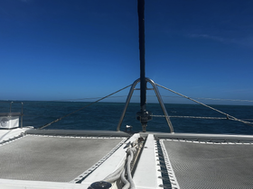 A clear view of a catamaran sailing on open waters under a bright blue sky, showcasing the vessel's structure and design.