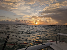 A serene sunset view from a catamaran, showcasing the tranquil waters and vibrant sky, perfect for evening cruises.