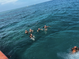 A lively group enjoys swimming in the clear blue waters, capturing the essence of fun and adventure on a boating trip.