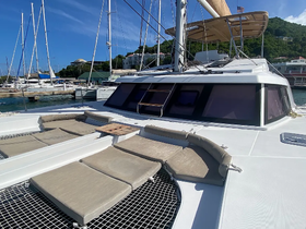 A spacious lounge area on a catamaran, featuring comfortable seating and a serene marina backdrop, perfect for relaxing on the water.