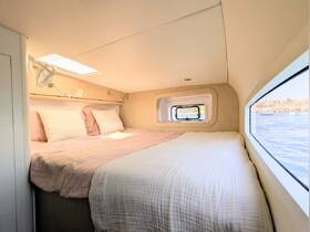 Cozy interior cabin featuring a comfortable double bed with natural light streaming in through large windows, perfect for relaxing on a boat getaway.