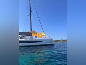 A stunning side view of the catamaran 'YEOMA' docked in crystal-clear waters, showcasing its sleek design against a bright blue sky.