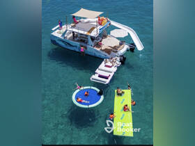 A lively group enjoys a fun day on the water with a boat featuring a slide, floating mats, and swimming activities — perfect for summer parties and family outings.