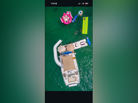 Aerial view of a lively group enjoying water activities around a boat, featuring a slide and floating mats — perfect for summer fun on the water.
