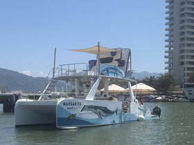 A stunning catamaran named 'Margarita' docked in calm waters, showcasing its vibrant design and spacious layout, perfect for local tours.