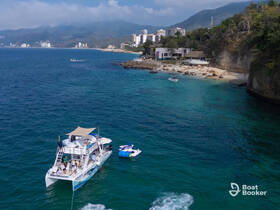 A lively group enjoys a day on a catamaran, anchored near a beautiful beach with clear waters — perfect for snorkeling and relaxation.