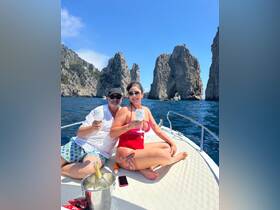 A couple enjoys cocktails on a boat surrounded by stunning rock formations, perfect for a memorable day on the water.