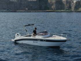 A man navigates a sleek boat on calm waters, showcasing the perfect day for a boating adventure along the scenic coastline.