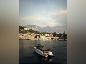 A scenic view of a boat navigating the tranquil waters of a lake, with picturesque mountains and colorful buildings in the background, perfect for exploring beautiful landscapes.