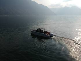 A sleek speedboat glides through calm waters, surrounded by stunning mountain scenery — perfect for adventure seekers and scenic tours.