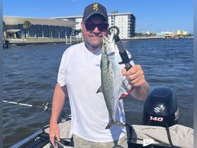 A proud angler holds up his catch while fishing from a boat, showcasing the thrill of a successful day on the water.