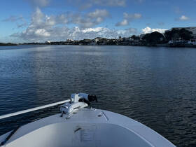 A serene view from the front of a boat navigating calm waters, showcasing the tranquil surroundings and waterfront properties.