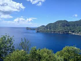 A stunning view of a serene coastline with lush green hills and clear blue waters, perfect for showcasing the natural beauty of the region.