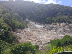 A view of a mountainous area with steam rising from the ground, showcasing the natural landscape but lacking clarity.