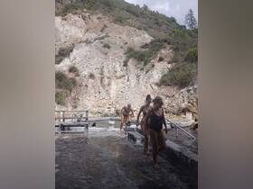 A group of friends enjoys a relaxing day at the hot springs, stepping into the warm waters surrounded by stunning natural scenery.