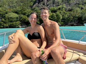 A happy couple enjoys a sunny day on a boat, surrounded by stunning turquoise waters — perfect for romantic getaways or tropical adventures.
