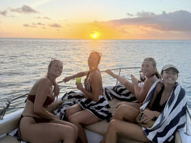 A group of friends enjoys a stunning sunset aboard a yacht, capturing the perfect moment of celebration and relaxation on the water.