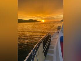 A stunning sunset view from the deck of a boat, showcasing the tranquil waters and silhouetted hills — perfect for evening cruises and relaxation.