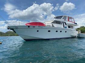 A stunning yacht named 'Bilanga' docked in clear waters, showcasing its elegant design against a backdrop of fluffy clouds and lush greenery.